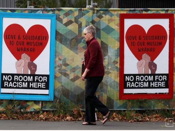 Orang ramai berjalan melepasi poster selepas serangan masjid di Christchurch, New Zealand, Jumaat lalu. - Foto Reuters/Jorge Silva
