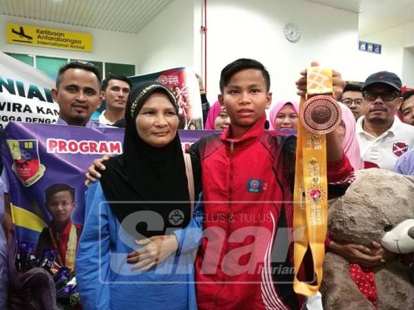 Muhammad Adam (kanan) bersama ibunya, Siti Rohaida menunjukkan pingat gangsa yang dimenanginya.