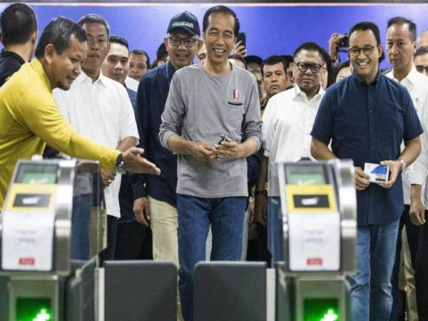 Jokowi (tengah) bersama beberapa pegawai kerajaan menyertai upacara perasmian MRT.
