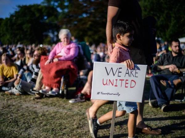 Seorang kanak-kanak memegang plakad bertulis 'Kami Bersatu' ketika menghadiri himpunan mengenang mangsa serangan masjid di Christchurch pada 15 Mac lalu. - Foto AFP