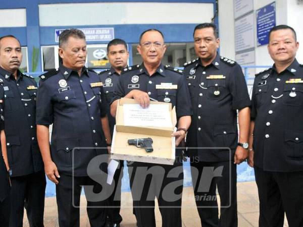 Omar Bakhtiar menunjukkan pistol tiruan yang dirampas daripada suspek, hari ini.