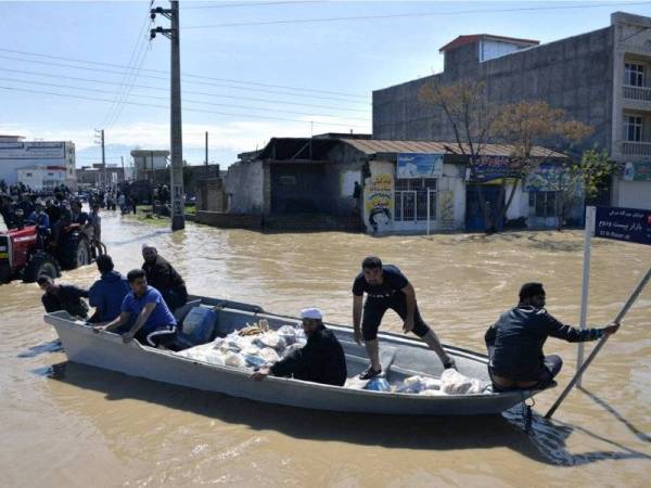 Penduduk Kampung Agh Ghaleh di utara Iran menggunakan bot bagi mengharungi jalan yang dinaiki banjir.- Foto AFP
