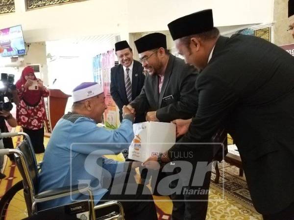 Mujahid (tengah) menyampaikan sumbangan ketika merasmikan Konvensyen Masjid Model Rahmah di Masjid Al Malik Khalid USM tadi.