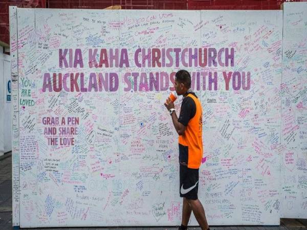 Seorang lelaki melihat dinding khas di Auckland yang dipenuhi pesanan bagi memperingati mangsa serangan berdarah di Christchurch. 