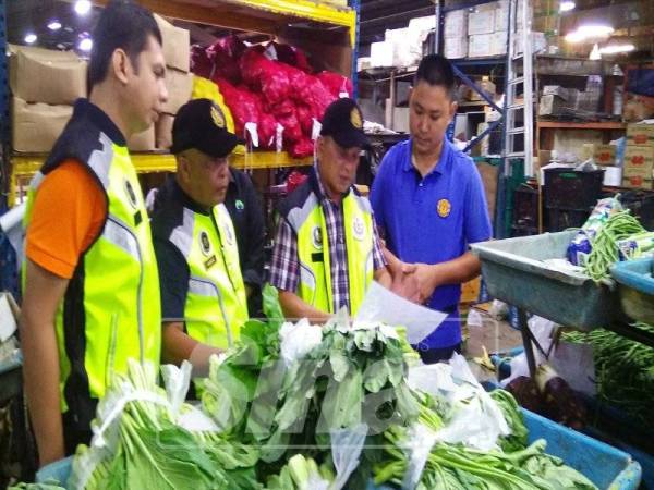 Samudin (dua, kanan) melihat tanda harga yang terdapat di sebuah kedai menjual sayur-sayuran dalam operasi bersepadu itu.