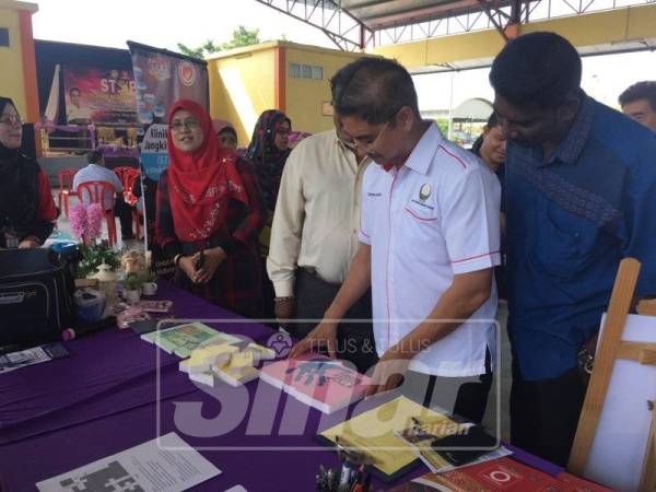 Terence (tengah) mencuba permainan susun gambar di salah sebuah booth pada program berkenaan di sini hari ini.