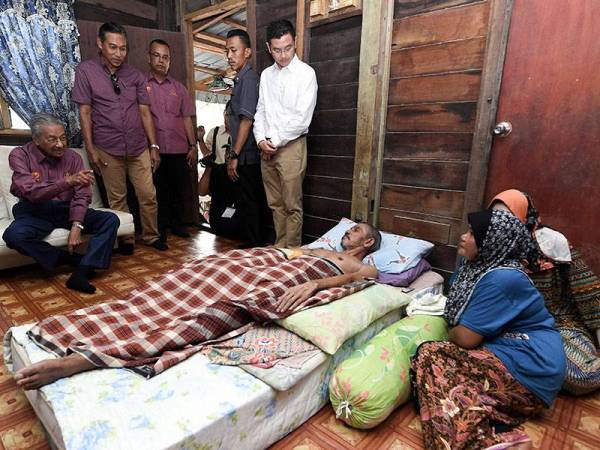 Perdana Menteri Tun Dr Mahathir Mohamad beramah mesra bersama pesakit lelaki yang lumpuh Othman Bakar, 66, dalam lawatan ke rumah asnaf di Sungai Kelibang Kuah hari ini. - Foto Bernama