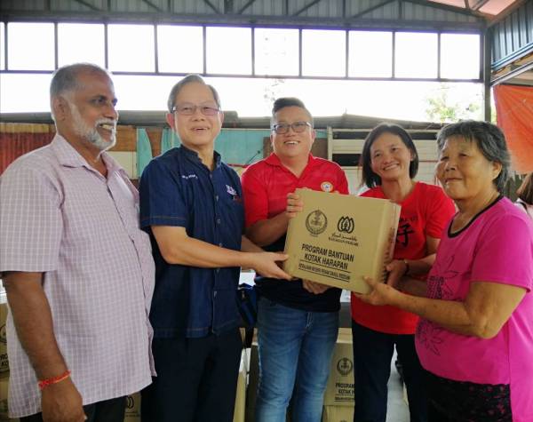 Boon Chye (dua, kiri) menyampaikan kotak makanan dibawah program bantuan kotak harapan kepada penduduk Kampung MTD.
