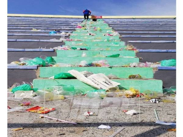 Seorang pekerja Perbadanan Stadium Negeri Kedah sedang membersihkan sampah yang ditinggalkan dalam stadium tersebut.