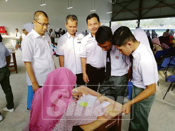 Ismail, Ishak dan Tumin melihat pelajar baharu yang mendaftar di SMKSM. 