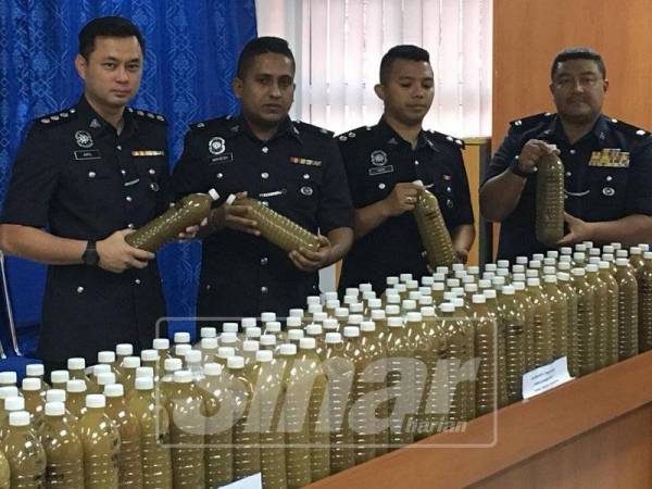 Norzamri (kanan) bersama pegawainya menunjukkan sebahagian daripada 170 botol air ketum yang dirampas di IPD Maran di sini, hari ini.