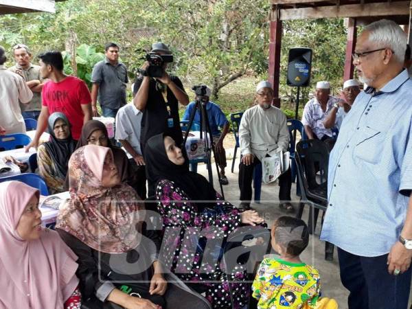 Mahfuz (kanan) mendengar perkongsian penduduk Kampung Padang Kunyit yang terjejas ribut pada Rabu dan Khamis lalu.