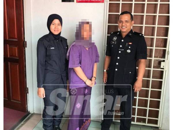 Tertuduh (tengah) dikawal polis keluar dari mahkamah selepas didakwa.