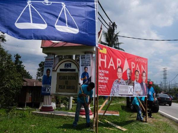 Petugas PH dilihat memasang poster kempen yang tertera gambar calon PH Dr S Streram, berhampiran papan tanda &#039;Selamat Datang Ke Rantau&#039; sempena tempoh berkempen PRK DUN N27 Rantau. Turut kelihatan bendera poster calon BN Datuk Seri Mohamad Hasan turut dipasang ditempat yang sama. -Foto Bernama