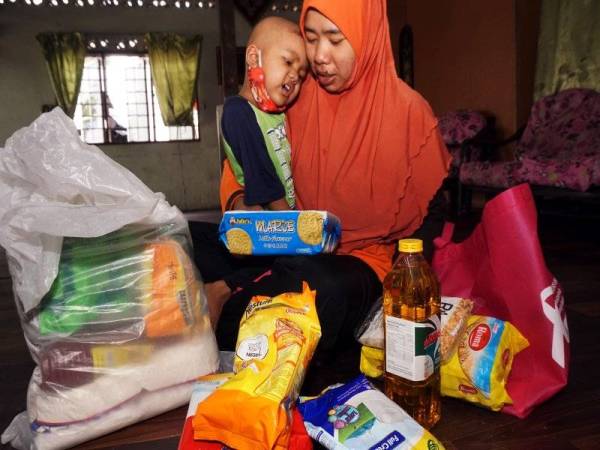 Nur Afiza (kanan) memujuk Nurul Izati Husna Mohd Buyamin berusia tiga tahun yang mengidap penyakit leukemia di rumahnya di Kampung Telok Malek hari ini. - Foto Bernama