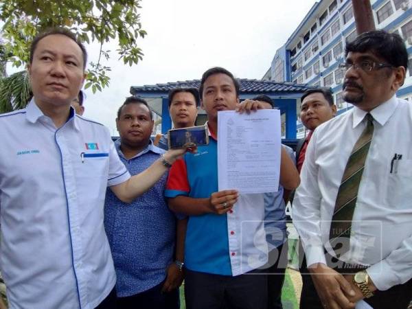 Fahmi (tengah) bersama Jason (kiri) menunjukkan laporan polis yang dibuat terhadap Raggie di IPDTL hari ini.