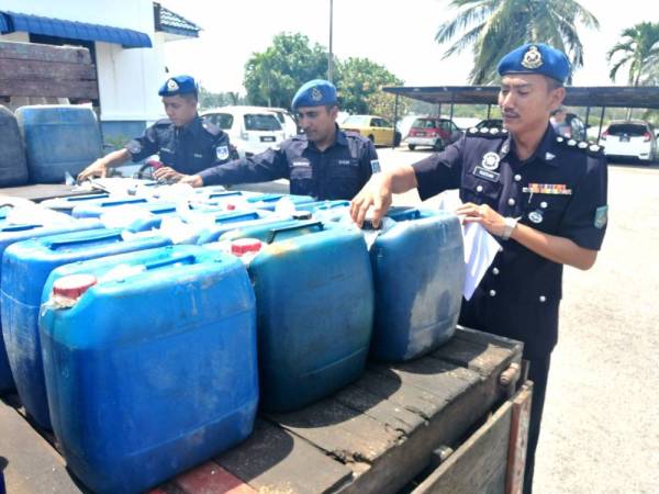 Mohd Rudzuan (depan) bersama anggotanya memeriksa diesel yang dirampas si Markas PPM Pengkalan Kubor.