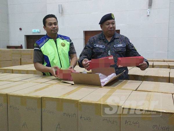 Abdul Latif (kanan) bersama kotak rokok dirampas pada sidang media di Kompleks KDN Anak Bukit hari ini.