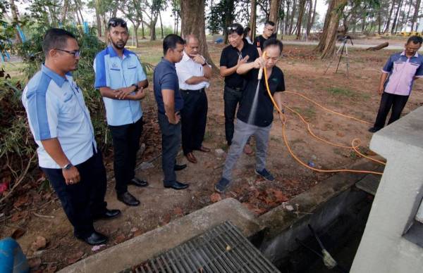 Tahir (empat, kiri) melihat wakil syarikat yang membuat semburan bahan organik pada longkang bagi menghilangkan bau di pusat perniagaan di Taman Gelora, hari ini.