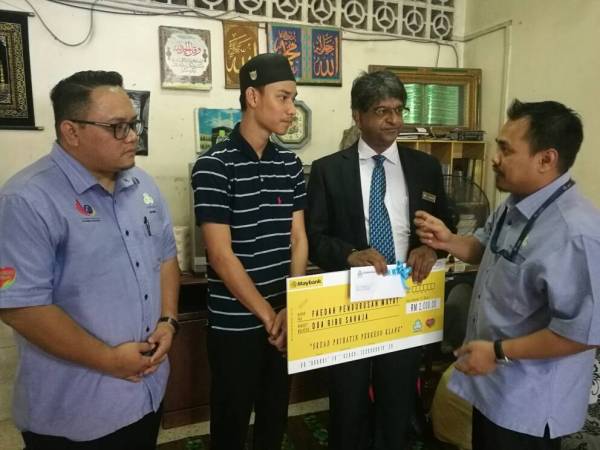 V. Mohanadas (dua, kanan) menyampaikan faedah pengurusan jenazah sebanyak RM2,000 kepada Amirul (dua,kiri) ketika program kunjungan penyampaian faedah oleh Skuad Perkeso Prihatin daripada Perkeso Klang di Taman Rashna di sini tadi.