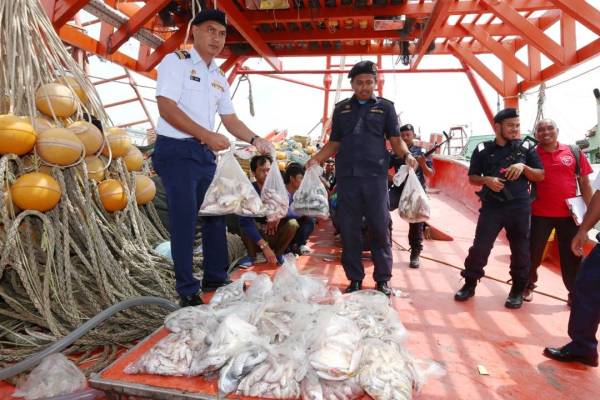 Rashidilhadi (kiri) menunjukkan sebahagian hasil tangkapan laut yang dirampas.