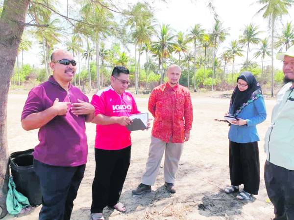 Md Zali (kiri) memberikan taklimat ketika lawatan ke Pantai Bisikan Bayu.