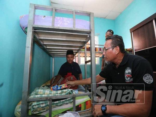 Amiruddin memeriksa barangan yang dibawa Mohd Firdaus ketika ditempatkan di bilik asrama Pertubuhan Badan Kebajikan Anak-anak Yatim Darussalam, hari ini. 