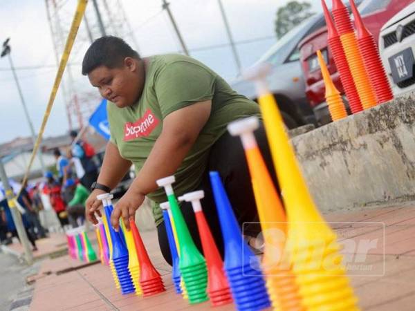 Muhd Farhan sedang menyusun vuvuzela untuk dijual sempena PRK DUN Rantau, di sini, hari ini. - Foto Adam Amir Hamzah