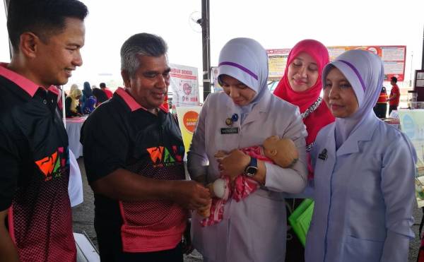 Mohd (dua, kiri) melihat bahagian suntikan imunisasi yang dilakukan terhadap bayi yang dipamerkan sempena Kempen Hidup Aktif - Walk Peringkat Negeri 2019 di Dataran Shahbandar, semalam.