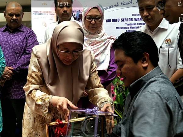 Dr Wan Azizah menyampaikan anugerah Penghargaan Khas OKU Cemerlang kepada Mohd Huzairee Ahmad (kanan) dalam Program Santuni Rakyat Negeri Pahang dan Mini Job Fair di Kompleks Beli Belah Megamall di sini hari ini.