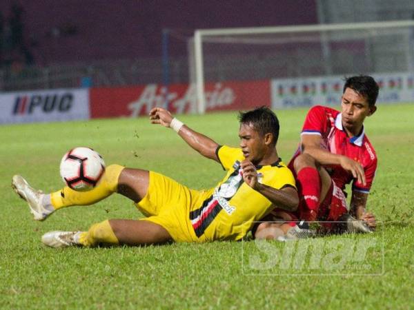 Pertahanan Kelantan, Mohd Shahrul Nizam Ros Hasni (kanan) mengasak daripada belakang pemain PDRM pada pertemuan kedua-dua pasukan dalam aksi Liga Premier di Kota Bharu, malam tadi.