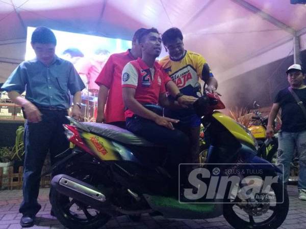 Muhammad Shafie bersama motosikal yang dimenanginya pada acara cabutan bertuah dalam program Retromania Grand Gathering 2019 di Pantai Morib, semalam.