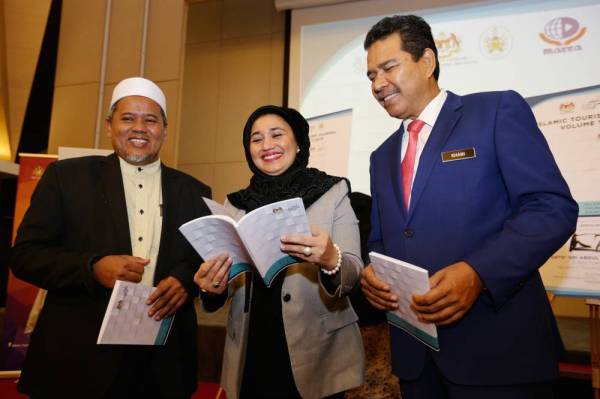 Abdul Khani (kanan) melihat jurnal pelancongan Islam bersama Haslina (tengah) selepas selesai perasmian Symposium On Islamic Tourism 2019 dan Majlis Pelancaran Islamic Tourism Journal Vol.1 2019 di Hotel Paya Bunga, di sini hari ini.