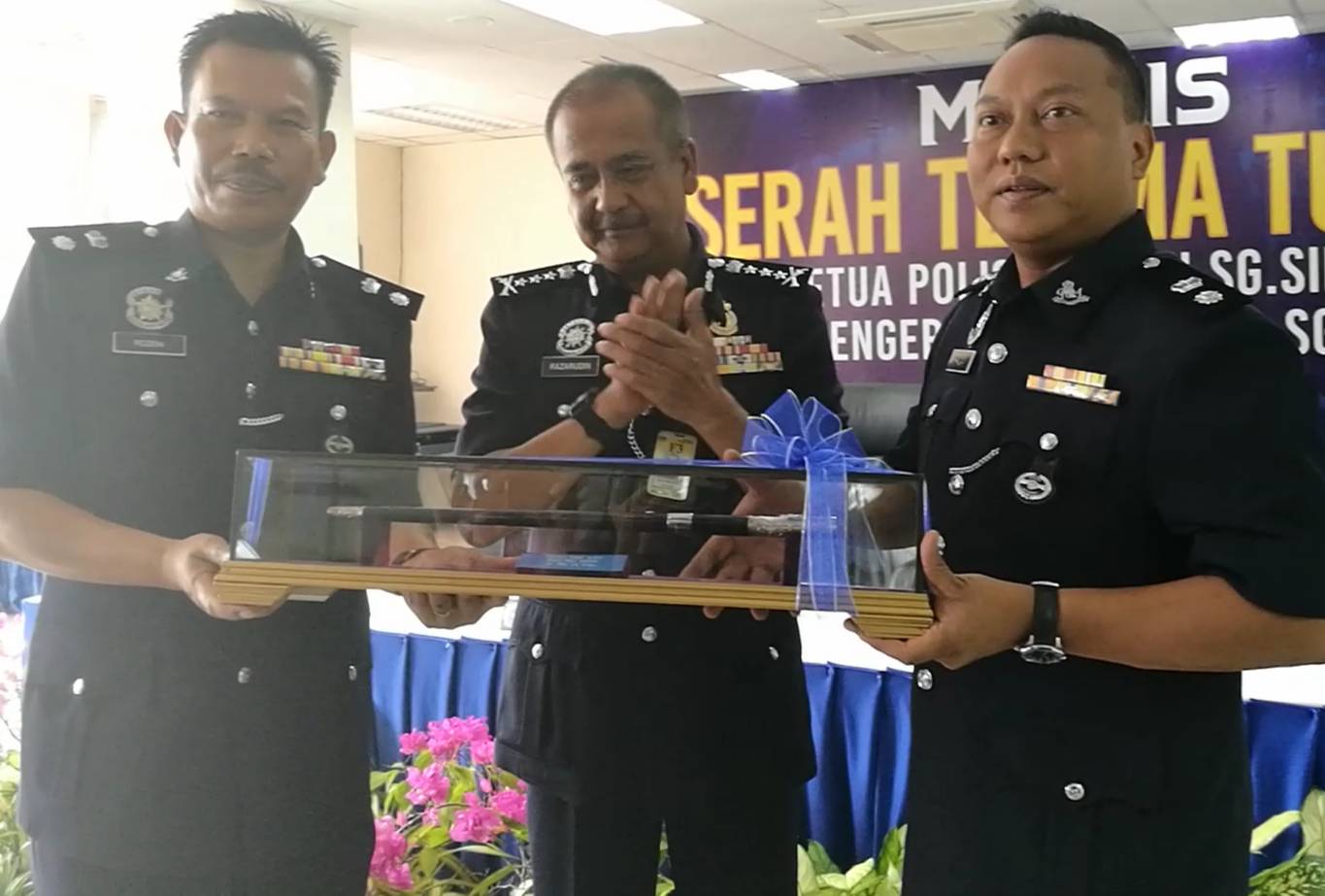 Mohd Khaizam (kanan) menerima tongkat kuasa daripada Rozeni sambil diperhatikan Razarudin.
