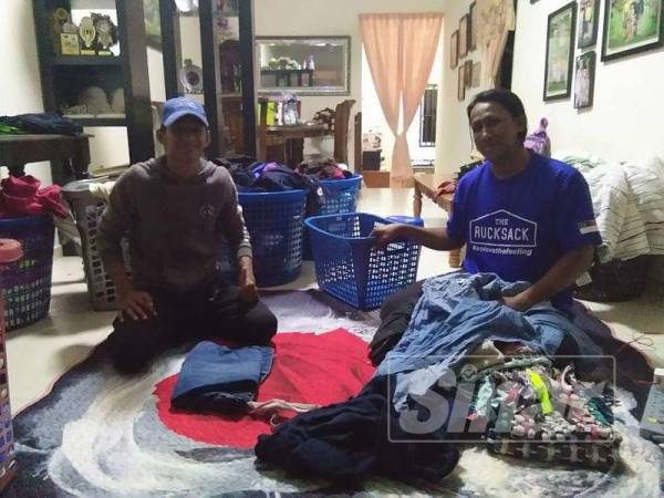 Omar (kanan) melipat kain di sebuah rumah pelanggan bersama pekerjanya.