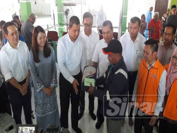 Sahruddin (tiga dari kiri) menyerahkan sumbangan kepada penduduk yang terjejas dengan insiden letupan dan kebakaran Rapid, Pengerang di Masjid Kampung Lepau, semalam. 