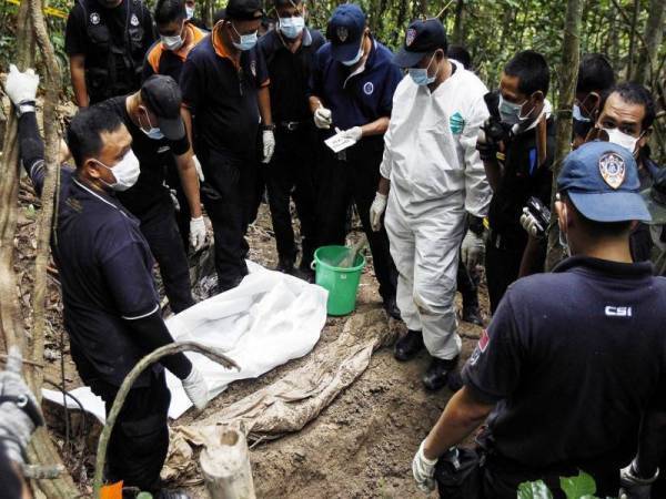 Anggota forensik Polis DiRaja Malaysia memeriksa jenazah yang ditemui di kubur yang tidak ditanda berhampiran Wang Kelian di puncak Bukit Wang Burma di Wang Kelian yang terletak di sempadan Malaysia-Thailand. - Foto fail AP