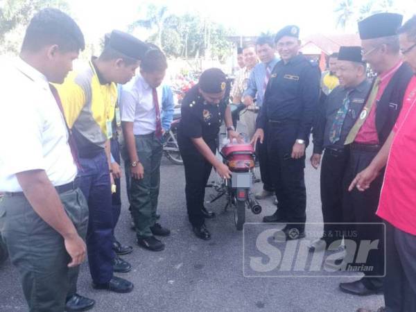 Che Mohd Hisham (empat dari kiri) memeriksa sebuah motosikal yang menggunakan nombor pendaftaran kecil tidak mengikut spesifikasi dalam pemeriksaan di sebuah sekolah menengah di Jertih hari ini.