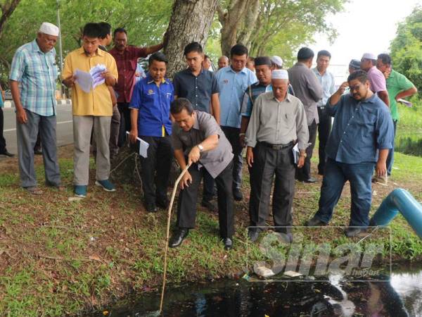 Azman memeriksa saluran pembentung yang menyebabkan limpahan air di kawasan sawah di sini, hari ini.