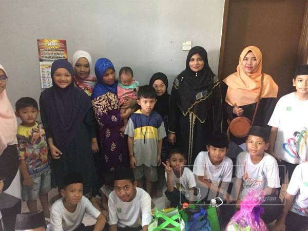 Rahilah (berdiri, tiga dari kanan) bersama para muridnya menyerahkan sumbangan 'Secebis Kasih, Sejuta Harapan' kepada salah sebuah keluarga yang dibantu.