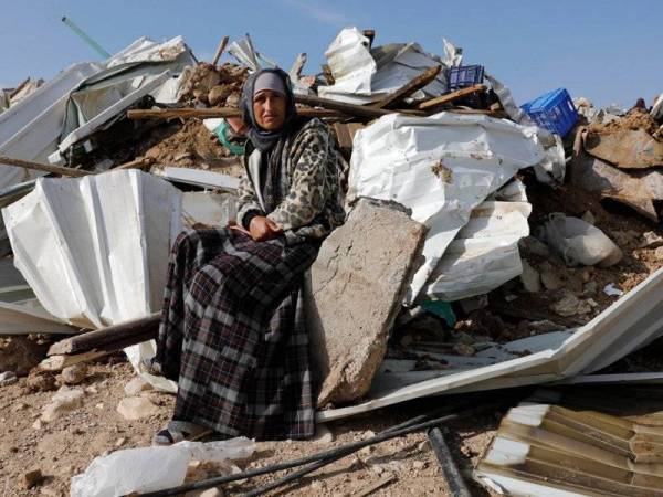 Seorang wanita Badwi Palestin duduk di hadapan sisa runtuhan pondoknya yang dimusnahkan tentera Israel.