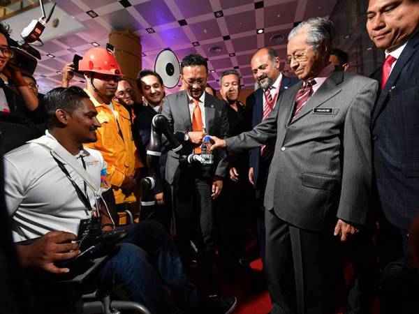 Perdana Menteri Tun Dr Mahathir Mohamad menerima sebotol air mineral daripada kerusi roda bertangan robot semasa melawat ruang pameran selepas perasmian '5G Malaysia Progressing Humanity Showcase' di Kompleks Perbadanan Putrajaya hari ini. - Foto Bernama