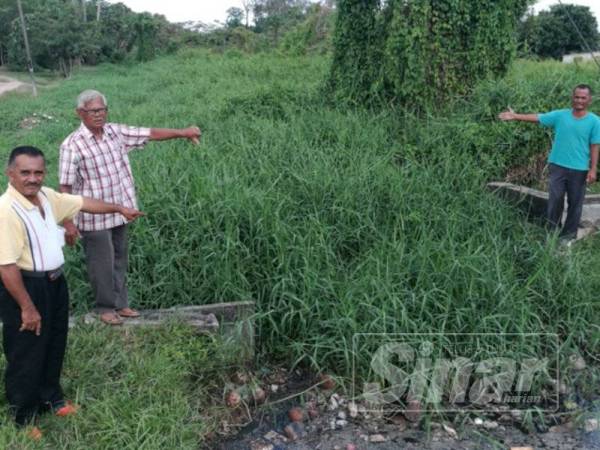 Dari kiri, Azlan, Abd Kamal dan Jefri menunjukkan longkang dipenuhi lalang menyebabkan air tersumbat.