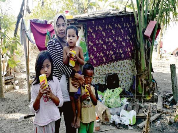 Rabiatuladawiyah bersama tiga anaknya di hadapan reban ayam yang dijadikan sebagai tempat tinggal mereka.