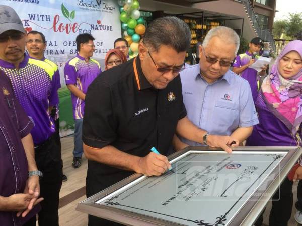 Sr Dzulkefly Ahmad menandatangani plak perasmian Galeri JLand di Bandar Tiram dekat sini hari ini.
