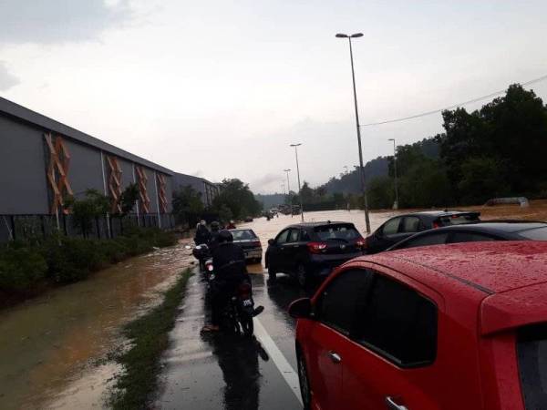 Pengguna jalan raya terpaksa menunggu dan ada yang berpatah balik apabila persimpangan tiga berhampiran Alam Budiman dilanda banjir kilat. (Gambar ihsan orang ramai)