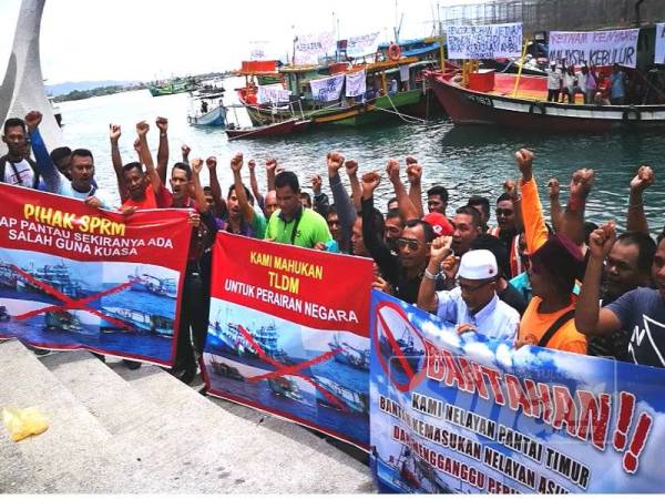 Kumpulan nelayan memegang gegantung memprotes tindakan nelayan asing menceroboh perairan negara.