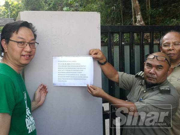 Jimmy Puah ( dua dari kiri) melihat notis berkenaan permit kemasukan Hutan Lipur Gunung Pulai 1 melebihi aras 1 ditanggalkan oleh Nazib (dua dari kanan).