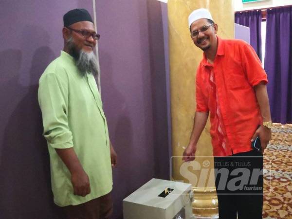 Mohd Arif (kiri) dan Baharuddin menunjukkan tabung masjid yang menjadi sasaran pencuri berkenaan.
