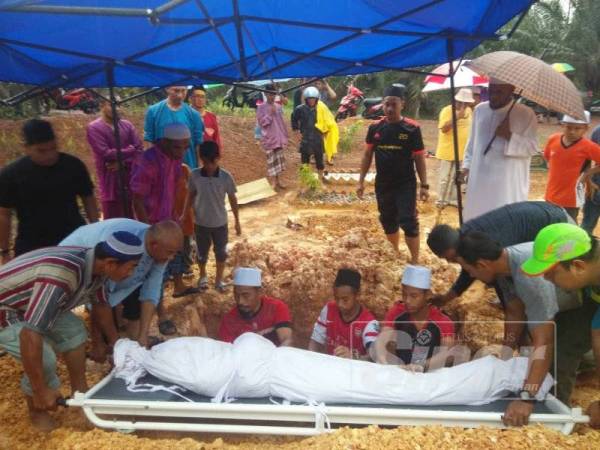 Mazeni (kiri) dan Muhammad Afiq (kanan) menyambut jenazah Mohammad Ammar di Tanah Perkuburan Islam Kampung Isnin Maarof, Simpang Renggam, petang tadi.